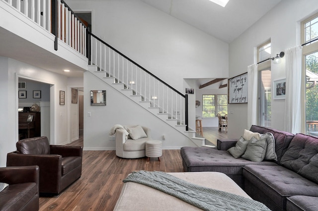 living room with stairs, dark wood finished floors, a towering ceiling, and baseboards