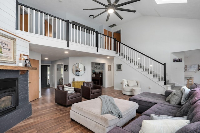 living room with stairs, a stone fireplace, wood finished floors, and visible vents