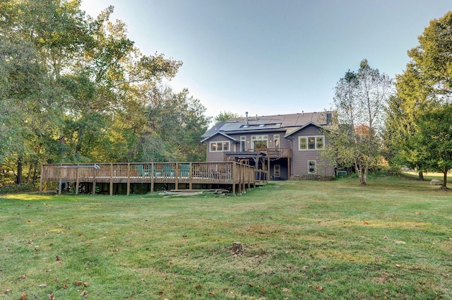 back of property with solar panels, a yard, and a wooden deck