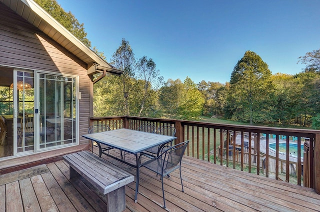 wooden terrace with outdoor dining area and an outdoor pool