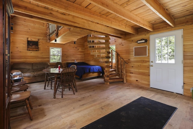 interior space featuring wood walls, beamed ceiling, and light wood-style floors