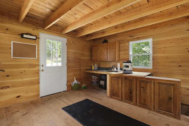 kitchen with light countertops, a healthy amount of sunlight, brown cabinets, and beamed ceiling