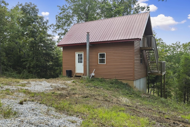 view of property exterior with entry steps, metal roof, and stairway