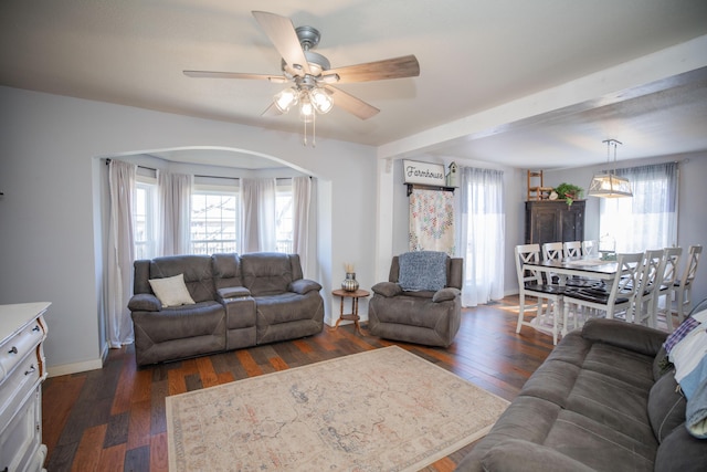 living room featuring baseboards, a ceiling fan, dark wood finished floors, and a wealth of natural light