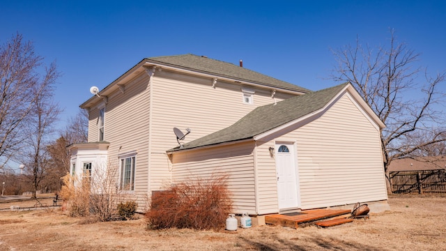 view of property exterior featuring a shingled roof and fence