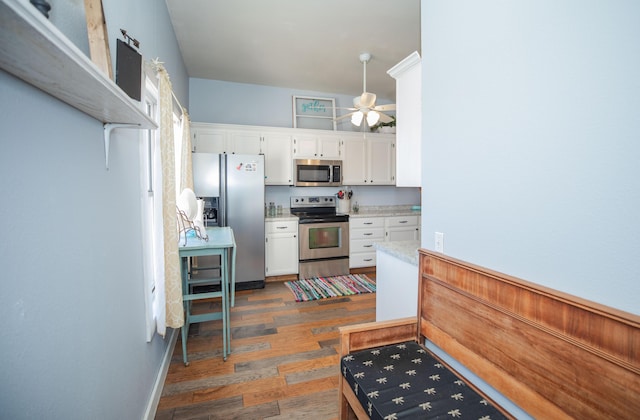 kitchen featuring dark wood-type flooring, a ceiling fan, white cabinets, light countertops, and appliances with stainless steel finishes