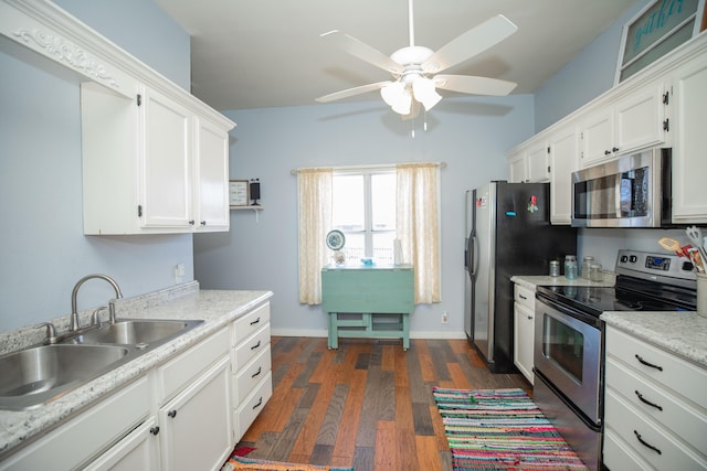 kitchen featuring appliances with stainless steel finishes, dark wood-style flooring, light countertops, white cabinetry, and a sink