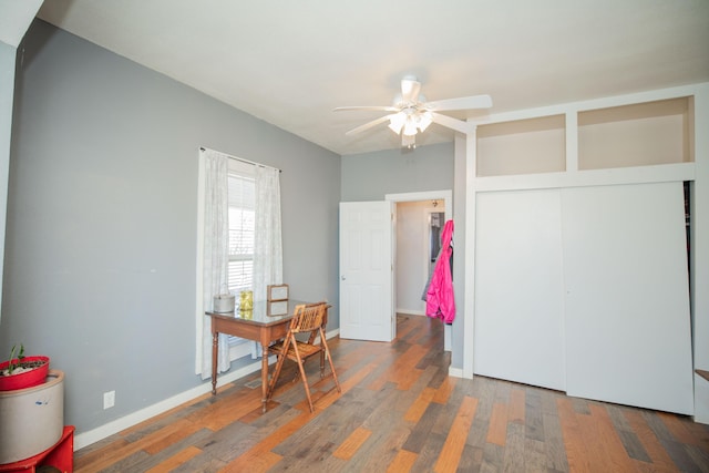 interior space with a closet, wood finished floors, a ceiling fan, and baseboards