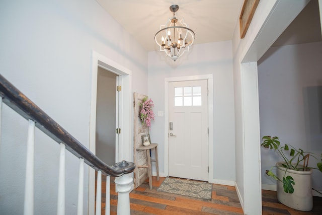 entryway featuring a notable chandelier, baseboards, stairway, and wood finished floors