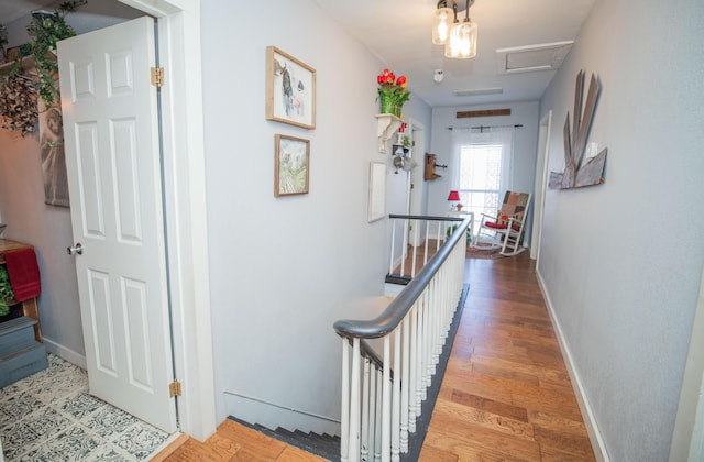 hall with attic access, baseboards, wood finished floors, and an upstairs landing