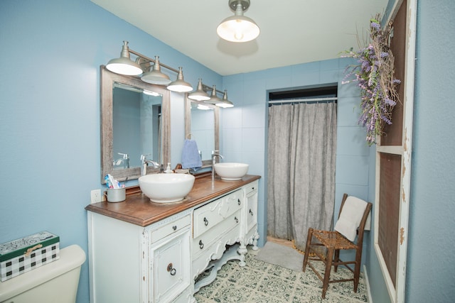 full bathroom with toilet, a shower with curtain, double vanity, and a sink