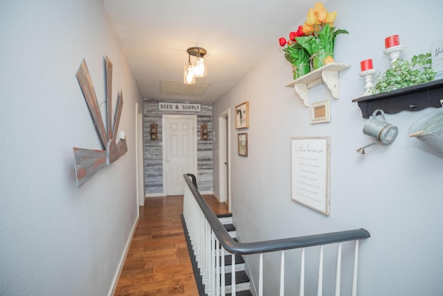 hallway with baseboards, an upstairs landing, and wood finished floors