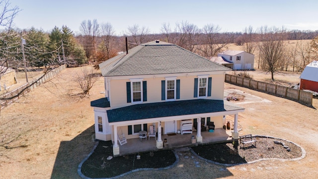 view of front of house with a shingled roof, a patio area, and a fenced backyard