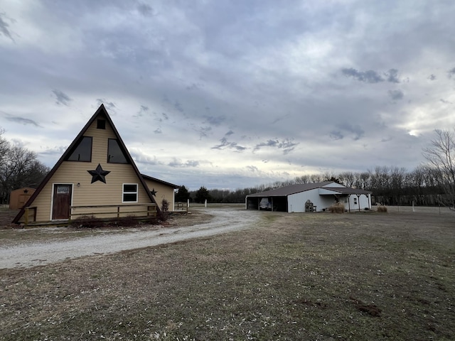 view of side of home featuring dirt driveway, a carport, and an outdoor structure