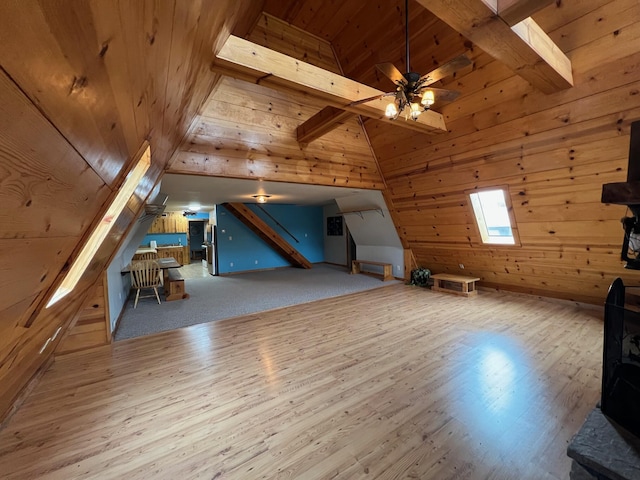 additional living space with wooden walls, lofted ceiling with beams, wood ceiling, ceiling fan, and wood finished floors