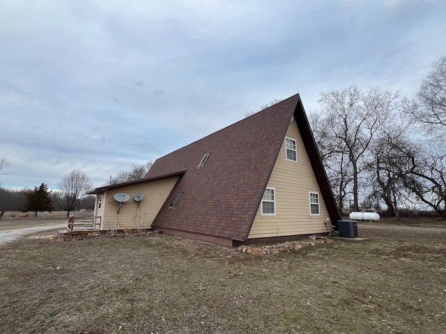 view of side of property with cooling unit and roof with shingles