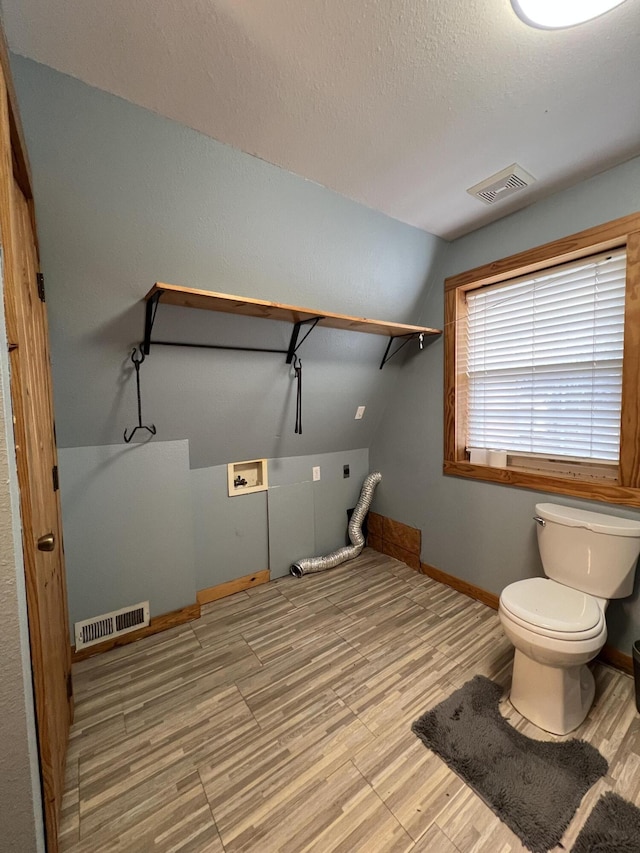 bathroom featuring baseboards, visible vents, toilet, and wood finished floors