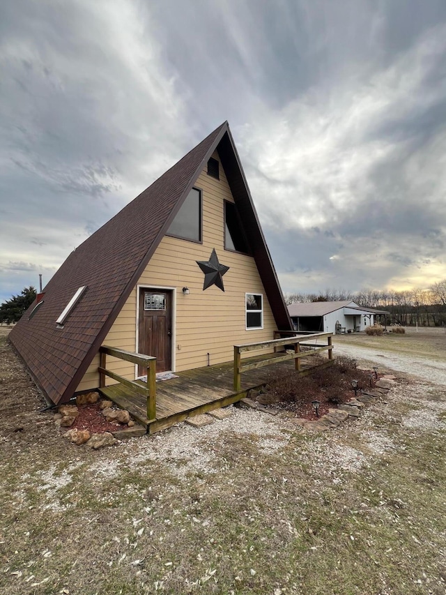 view of side of home featuring roof with shingles and a wooden deck