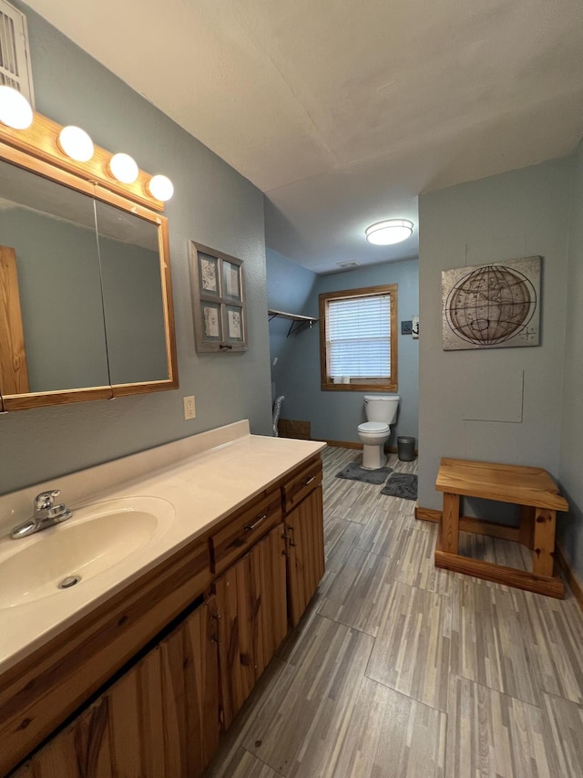 bathroom featuring toilet, baseboards, wood finished floors, and vanity