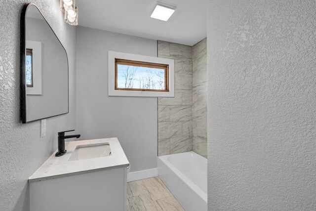 bathroom featuring marble finish floor, a textured wall, vanity, and baseboards