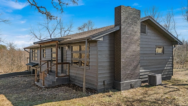 view of side of home featuring a chimney and cooling unit