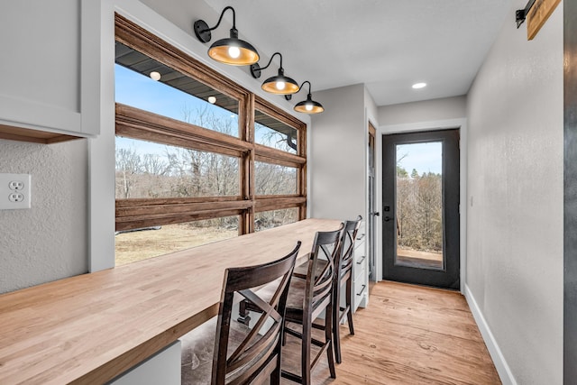 dining area with a textured wall, light wood-type flooring, and baseboards