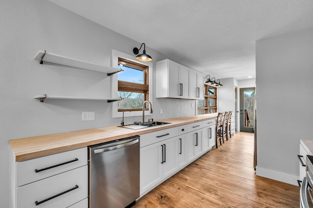 kitchen with a sink, wooden counters, stainless steel dishwasher, and open shelves