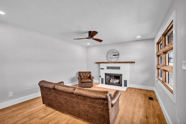 living area with recessed lighting, a brick fireplace, wood finished floors, and baseboards