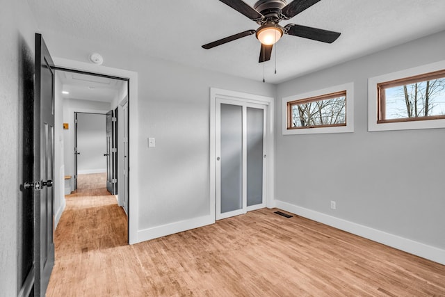 unfurnished bedroom featuring a closet, visible vents, light wood-style flooring, a textured ceiling, and baseboards