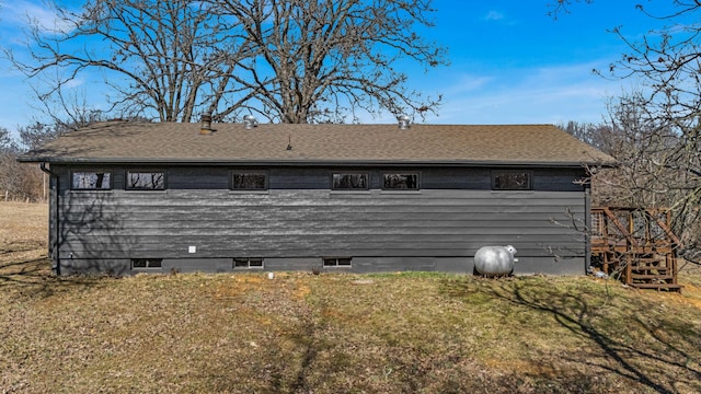 exterior space with roof with shingles and a lawn