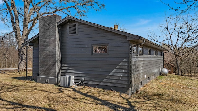 view of side of property featuring central AC, a lawn, and a chimney