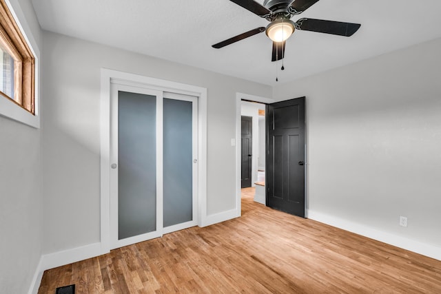 unfurnished bedroom featuring a closet, visible vents, a ceiling fan, wood finished floors, and baseboards