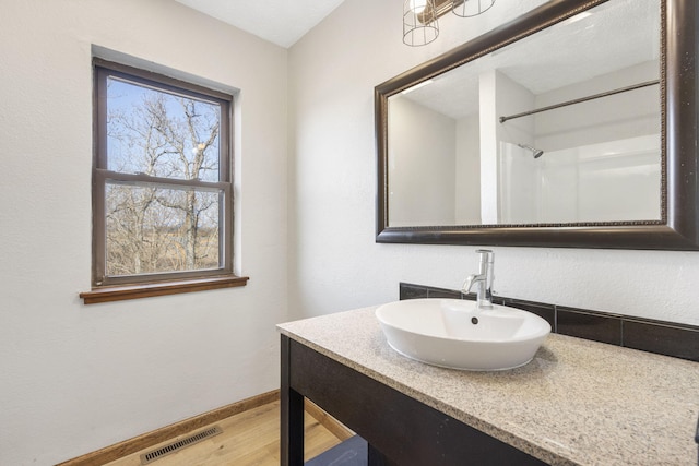 bathroom featuring baseboards, visible vents, wood finished floors, and vanity