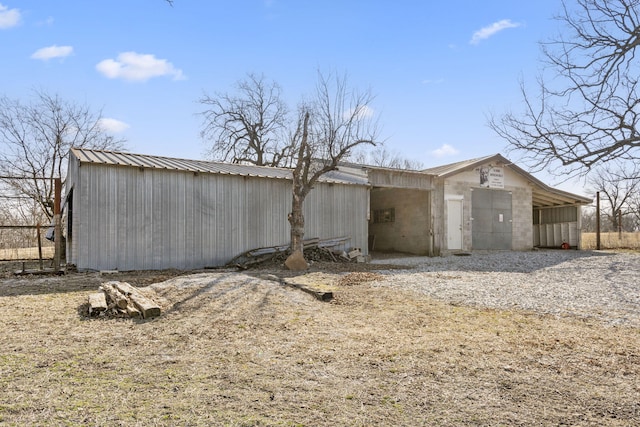 exterior space featuring metal roof, a pole building, an outdoor structure, and gravel driveway