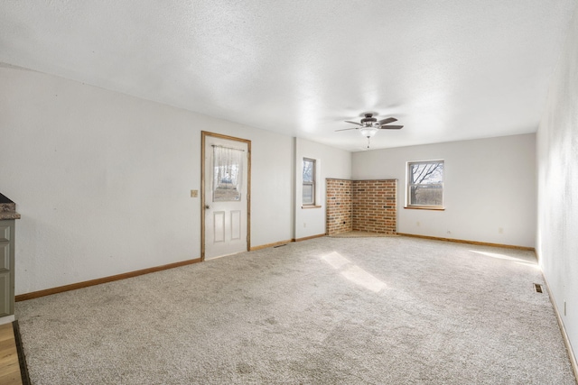 unfurnished living room featuring a ceiling fan, carpet flooring, a textured ceiling, and baseboards