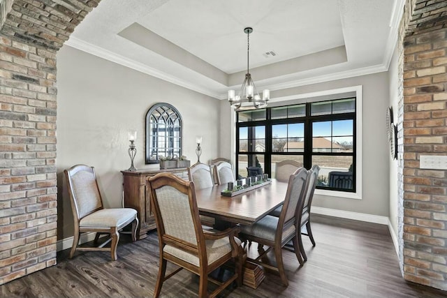 dining room with dark wood-type flooring, a notable chandelier, a raised ceiling, and a wealth of natural light