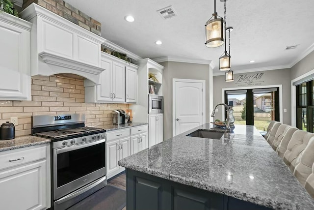 kitchen with stainless steel appliances, white cabinets, visible vents, and a sink