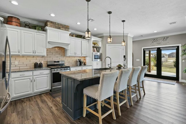 kitchen with white cabinets, light stone counters, stainless steel appliances, and a sink