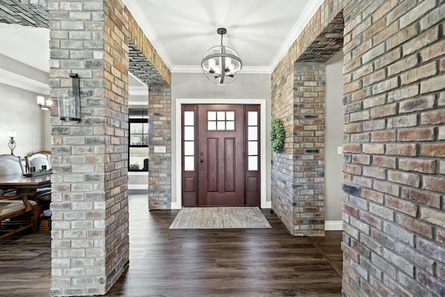 entryway with a chandelier, brick wall, dark wood-type flooring, baseboards, and ornamental molding