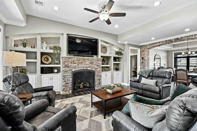 living area with visible vents, built in features, ornamental molding, light wood-type flooring, and a fireplace