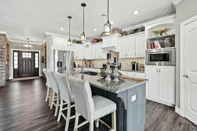 kitchen featuring stainless steel appliances, a sink, visible vents, ornamental molding, and dark wood-style floors