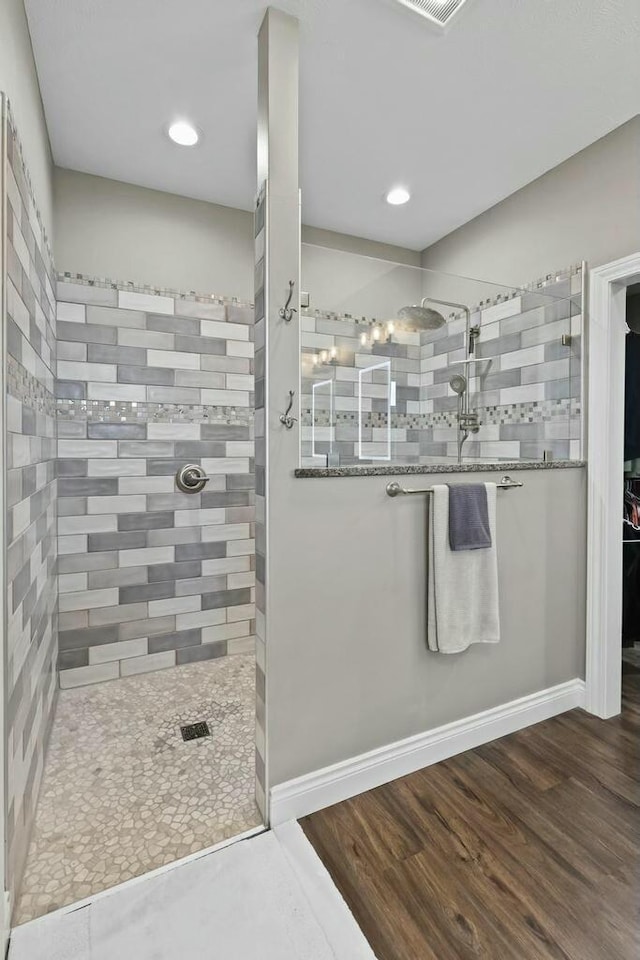 full bathroom featuring a walk in shower, baseboards, and wood finished floors