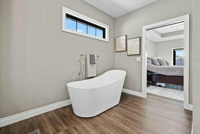 bathroom with wood finished floors, a soaking tub, connected bathroom, and baseboards