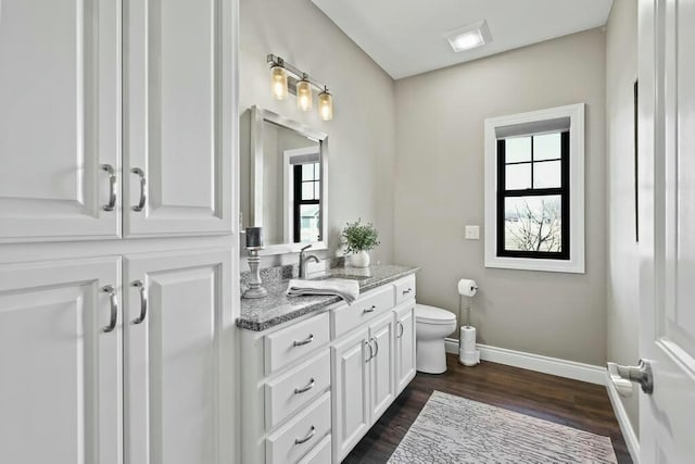 bathroom with vanity, wood finished floors, toilet, and baseboards