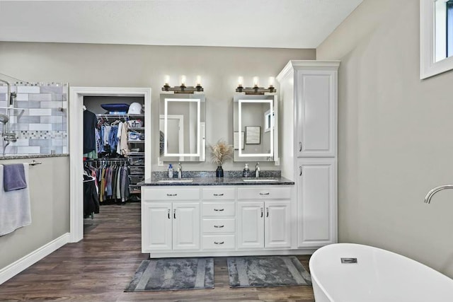 full bathroom featuring a freestanding bath, double vanity, wood finished floors, and a sink