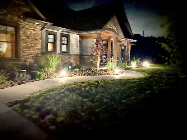 property exterior at night featuring stone siding