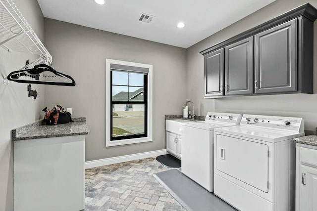 washroom featuring cabinet space, visible vents, washing machine and dryer, a sink, and baseboards