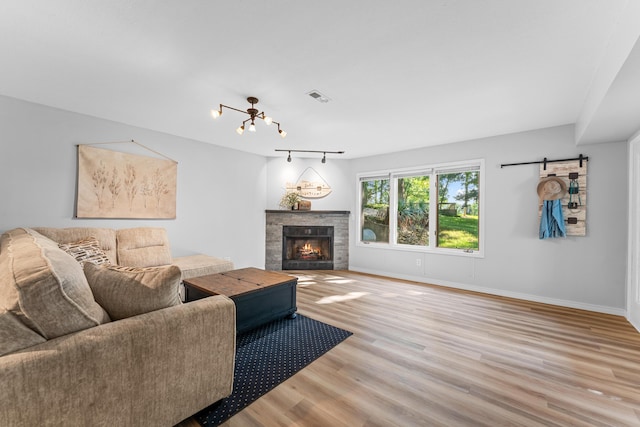 185 Eagle Pointe Dr, Branson, MO 65616 - living room featuring wood finished floors, a tiled fireplace, a barn door, and a chandelier