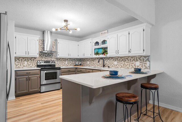 185 Eagle Pointe Dr, Branson, MO 65616 - kitchen with wall chimney range hood, stainless steel appliances, a peninsula, a kitchen breakfast bar, and light wood-style floors