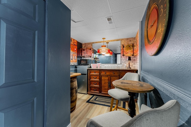 185 Eagle Pointe Dr, Branson, MO 65616 - kitchen featuring a paneled ceiling, light wood-style floors, freestanding refrigerator, decorative light fixtures, and brown cabinetry